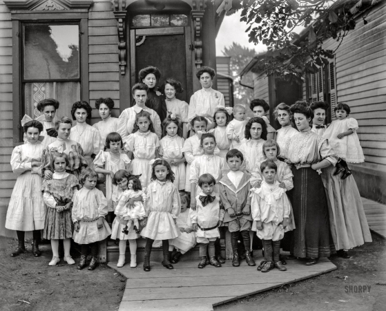 Photo showing: Lots of Tots -- Detroit circa 1910. Group in front of house, possibly schoolchildren and teachers.