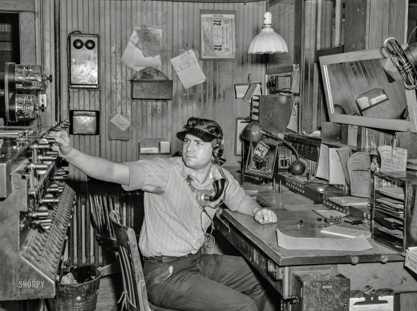 Photo showing: R.R. D.J. -- March 1943. Waynoka, Oklahoma. Santa Fe operator and telegrapher throwing one of the interlocking switches.